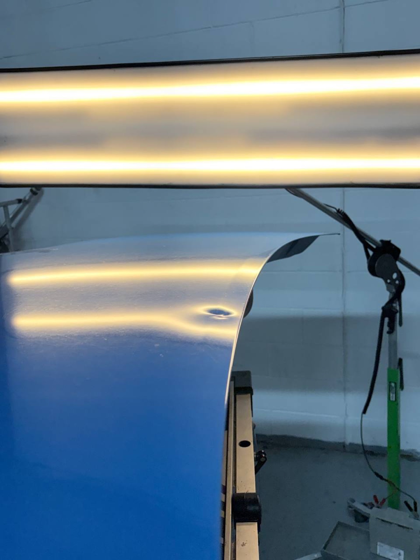 Blue vehicle quarter-panel crease before paintless dent repair, wider view