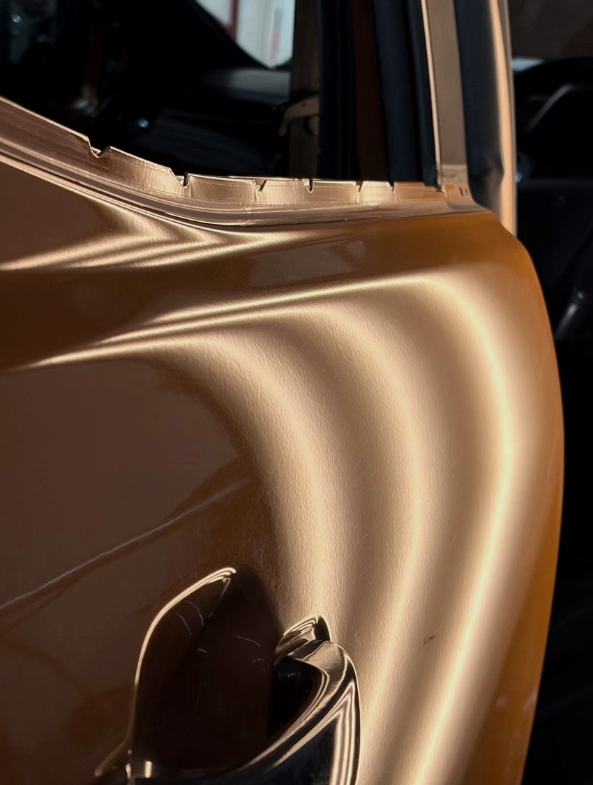 Door panel after paintless dent repair under inspection lighting